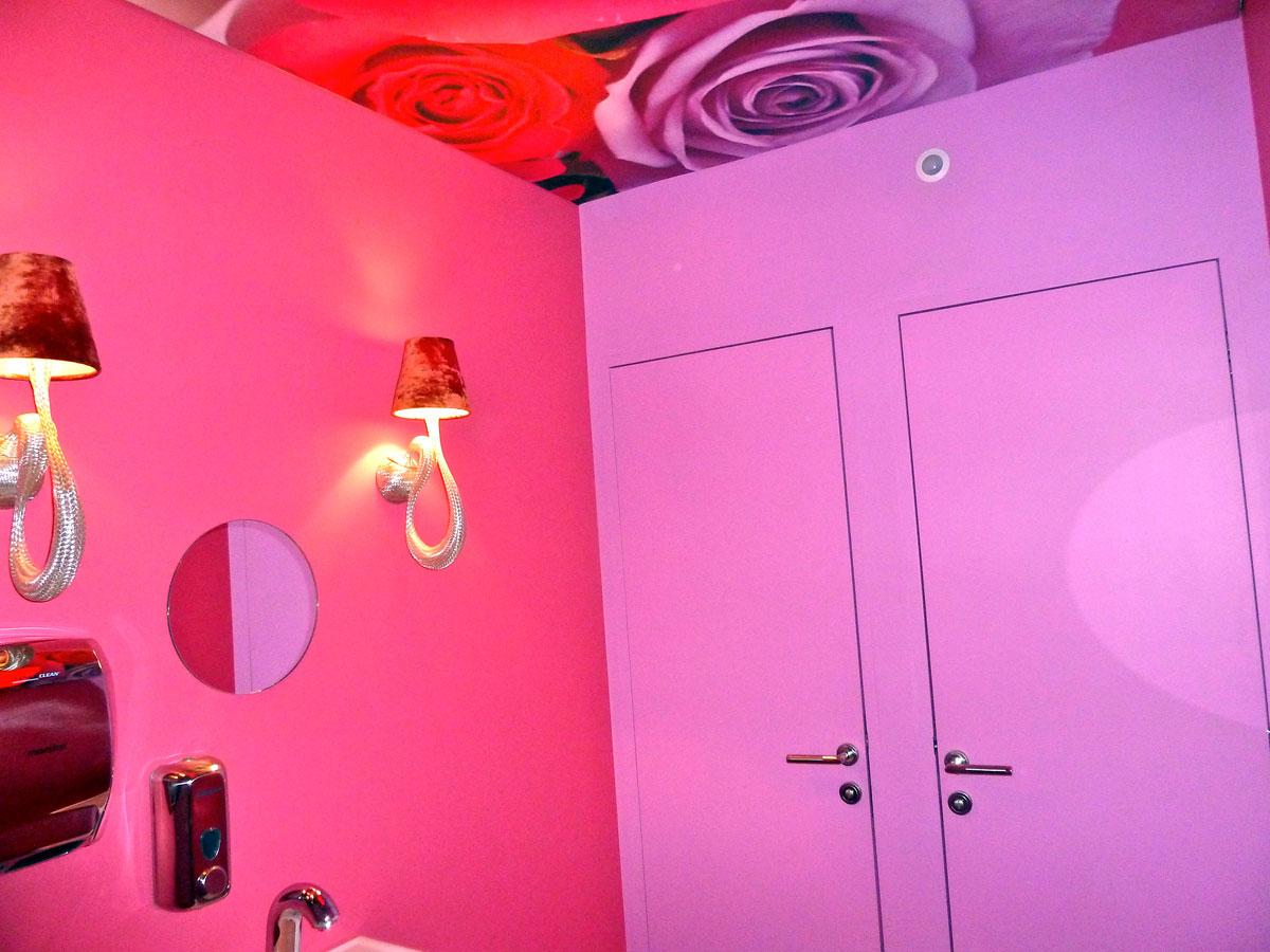 Pink powder room with rose wallpaper and wall lamps