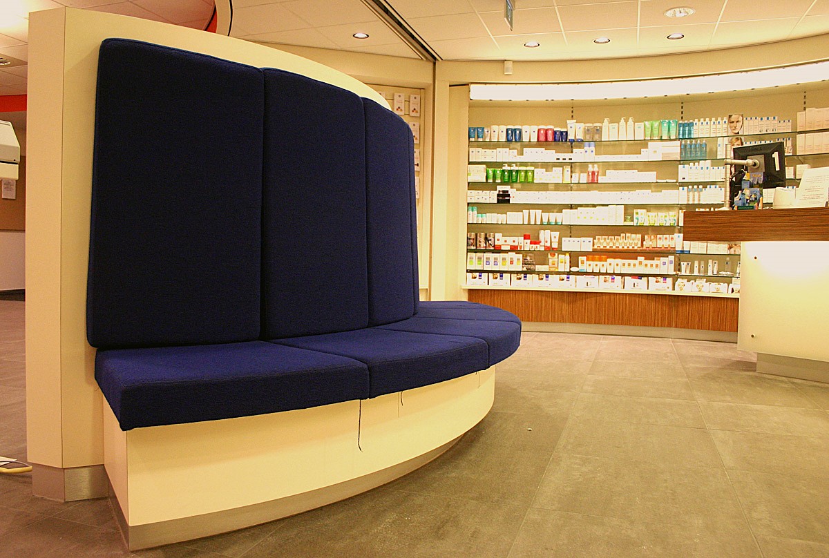 Curved blue waiting bench in front of a pharmacy wall